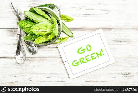 Green salad vegetables with tablet pc on kitchen table. Clean eating concept. Sample text Go Green