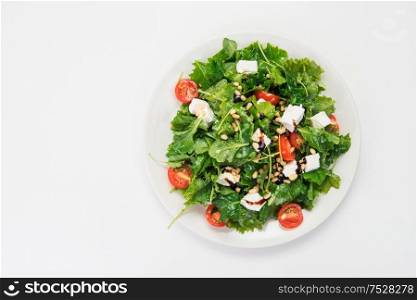 Green salad with vegetables: greens, arugula, tomato, cheese, pine nuts and sauce. Green salad with vegetables and cheese