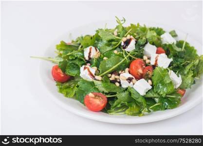 Green salad with vegetables: greens, arugula, tomato, cheese, pine nuts and sauce. Green salad with vegetables and cheese