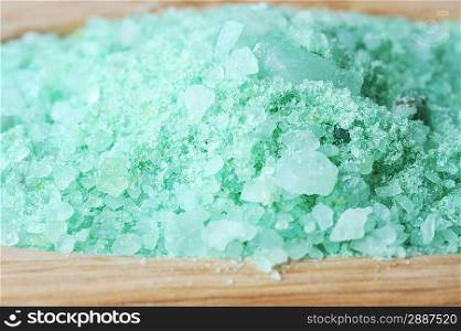 Green sea salt for bathing on wooden tray close up