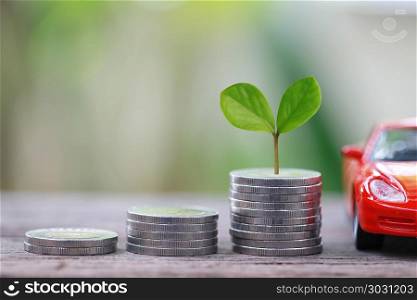Green Seedlings tree grow on coin money of graph business and re. Green Seedlings tree grow on coin money of graph business and red car in concept of investing and saving to buy a vehicle.