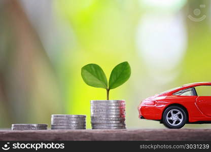 Green Seedlings tree grow on coin money of graph business and re. Green Seedlings tree grow on coin money of graph business and red car in concept of investing and saving to buy a vehicle.
