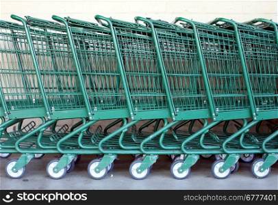 Green shopping carts together in a line up.