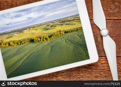 green soybean fields in a valley of the Missouri River, near Glasgow, MO, reviewing aerial image on a digital tablet