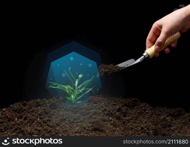 green sprout in a blue vacuum and a female hand with a shovel of earth on a black background. Environmental protection concept