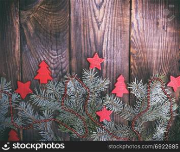 green spruce branch with Christmas decor on a brown wood background, empty space at the top, vintage toning