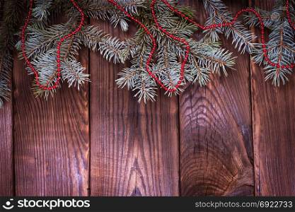 green spruce branch with Christmas decor on a brown wood background, empty space