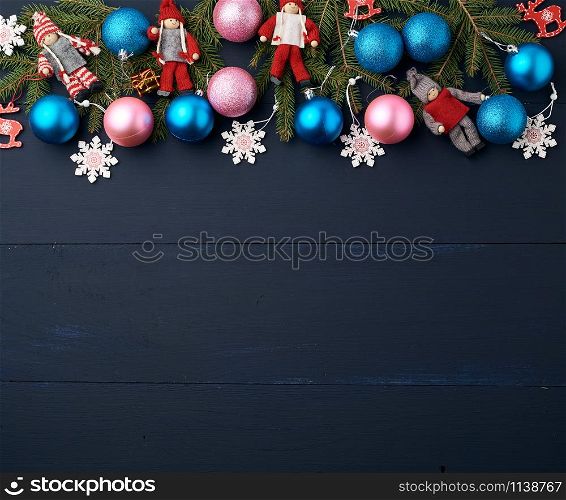 green spruce branches, Christmas blue and pink balls, carved wooden decor on a blue wooden background from boards, copy space