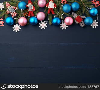 green spruce branches, Christmas blue and pink balls, carved wooden decor on a blue wooden background from boards, copy space