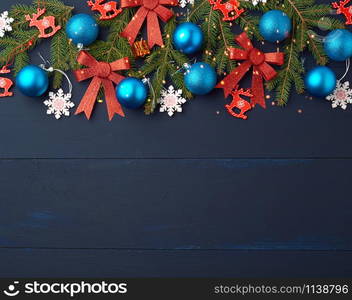 green spruce branches, Christmas blue and pink balls, carved wooden decor on a blue wooden background from boards, copy space