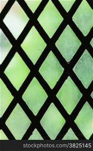 Green stained glass window with regular block pattern as background