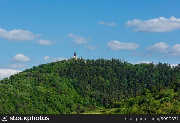 Green summer hill with forest and church tower on top (Slovakia)