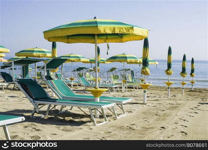 Green sunbeds and umbrellas on the beach.