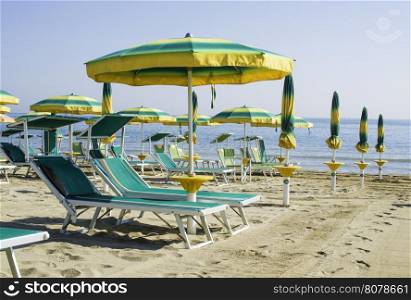 Green sunbeds and umbrellas on the beach.