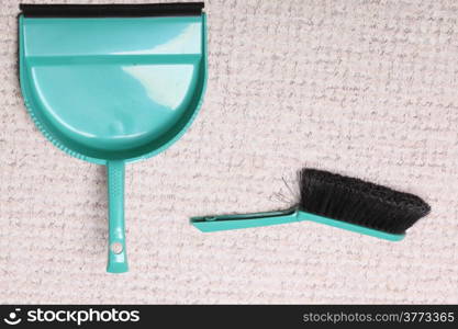 Green sweeping brush and dustpan for house work on floor indoors. Cleaning