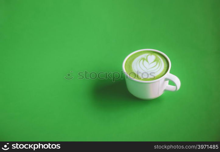 Green tea concept, Hot matcha green tea milk cream with art on top with white cup on green background for banner design with copy space. View from above.