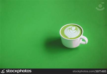 Green tea concept, Hot matcha green tea milk cream with art on top with white cup on green background for banner design with copy space. View from above.