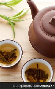 Green tea in brown mugs with teapot