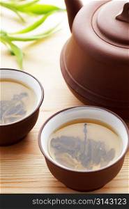 Green tea in brown mugs with teapot