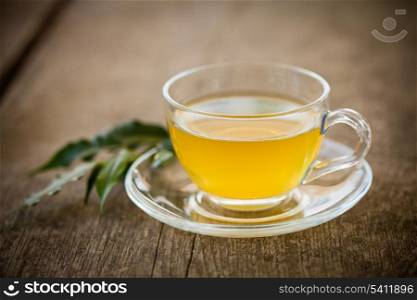 Green tea in glass cup and flowers on wooden table