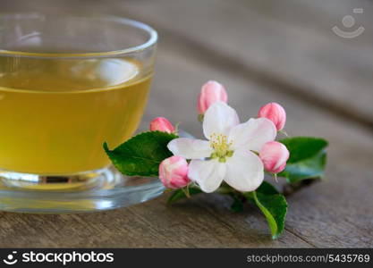 Green tea in glass cup and flowers on wooden table