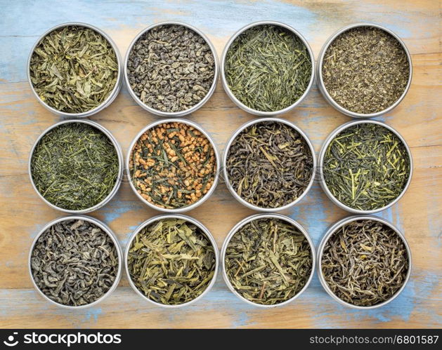 green tea sampler - top view of loose leaf teas in metal cans against grunge wood