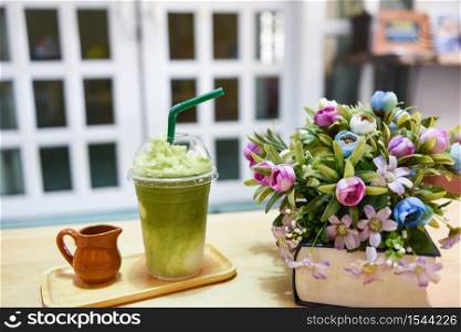 Green tea smoothie / Matcha green tea with milk on plastic glass on the table in a cafe