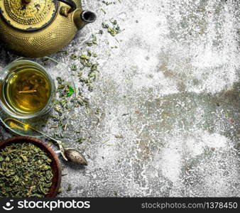 Green tea with a teapot. On a rustic background.. Green tea with a teapot.