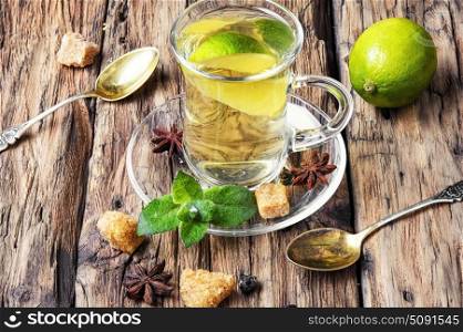 Green tea with lime, mint and sugar. Glass with tea with lemon and mint on saucer.Herbal tea.