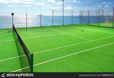 Green tennis court and blue sea.