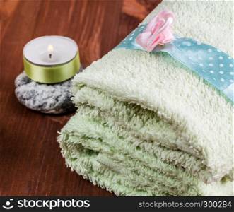 Green towel, candle, stone for the spa. Background for spa. Background for spa. Towel and candle on the stone