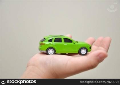 Green toy car on a right hand with white background. Green toy car on a right hand