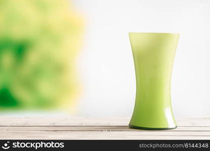 Green vase on a wooden table in the garden