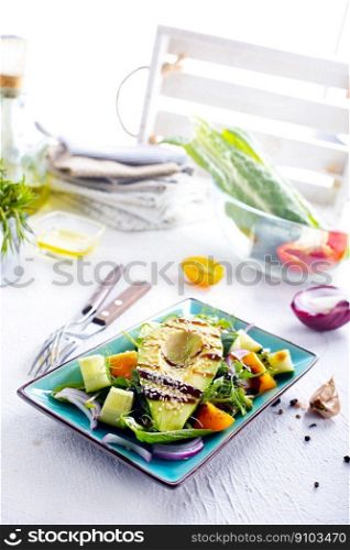 Green vegan salad with cucumber and avocado on a blue table. Green vegan salad with cucumber and avocado on a concrete table. View from above.
