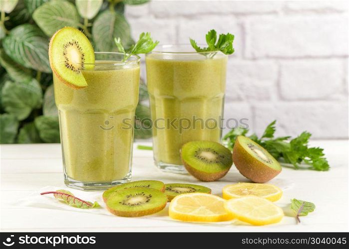 Green vegetable smoothie. Glasses of green vegetable smoothie. Green vegetable smoothie and ingredients: Kiwi, lemon and herbs.