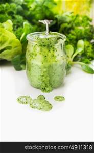Green vegetables smoothie in glass jar and spoon on white background