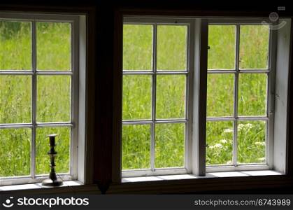 green view. view on a meadow out of old windows with a candle stick