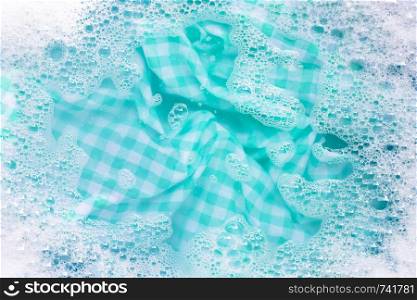 Green white tablecloth soak in powder detergent water dissolution. Laundry concept