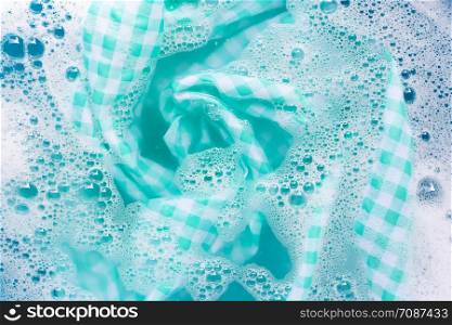 Green white tablecloth soak in powder detergent water dissolution, washing cloth. Laundry concept