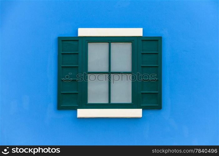 green window with shutters open on blue wall