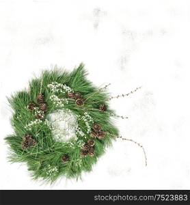 Green wreath with pine cones and white flowers. Christmas background. Top view