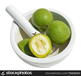 Green young walnuts in pounder on white background