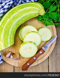 Green zucchini, garlic, parsley, napkin, knife on background wooden plank