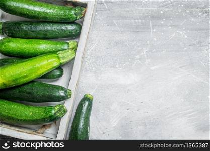 Green zucchini on tray. On white rustic background. Green zucchini on tray.