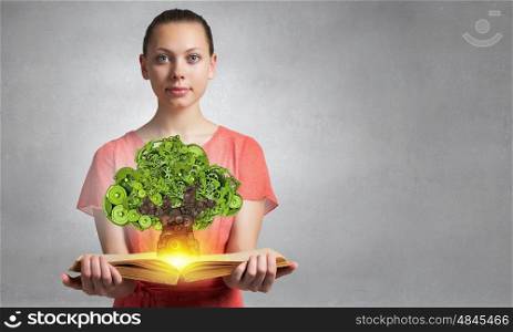 Greenery concept on book. Girl showing green concept with tree made of gears growing from book