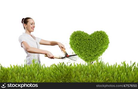 Greenery concept. Young attractive businesswoman cutting lawn in shape of heart