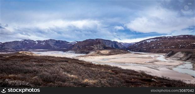 Greenlandic wastelands landscape with river and mountains in the background, Kangerlussuaq, Greenland