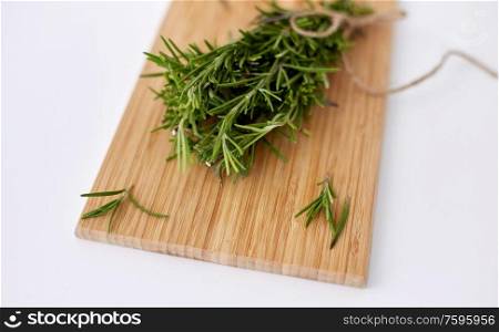 greens, culinary and ethnoscience concept - bunch of rosemary on wooden cutting board. bunch of rosemary on wooden cutting board