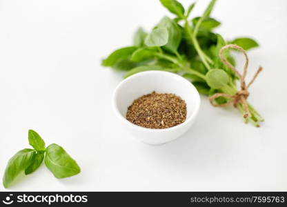 greens, culinary and flavoring concept - bunch of fresh basil herb and dry seasoning in cup on white background. fresh basil and dry seasoning on white background