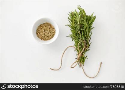 greens, culinary and flavoring concept - bunch of fresh rosemary herb and dry seasoning in cup on white background. fresh and dry rosemary on white background